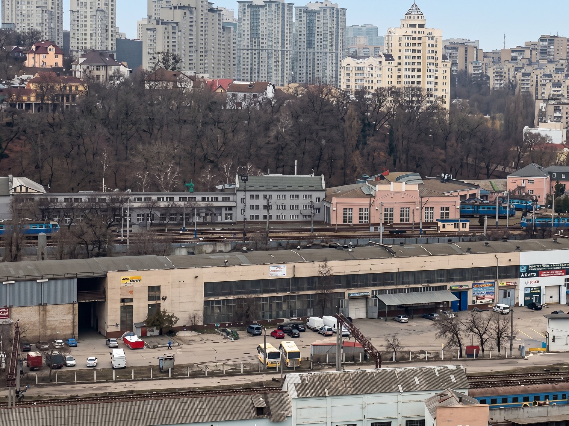 Комплекс у привокзальній зоні Києва: виробничий корпус на передньому плані, локомотивне депо і колії Центрального вокзалу, житлова забудова центру на горизонті
