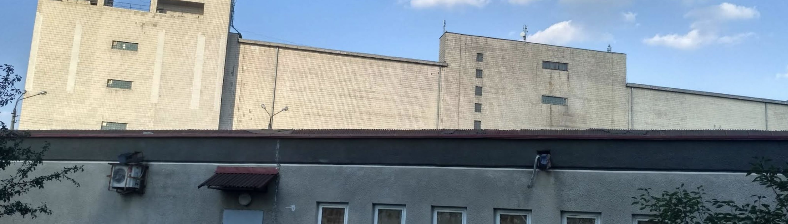 Корпуси холодильника з вулиці: два високі цегляні об'єми з вежами над лінією нижчої службової будівлі